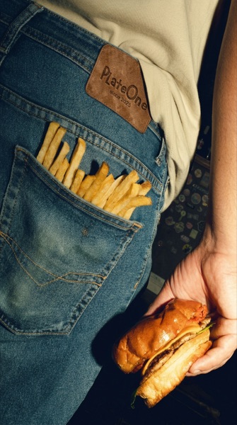 Des frites dans la poche arrière d’un jean, à côté d’un badge en cuir PlateOne.
